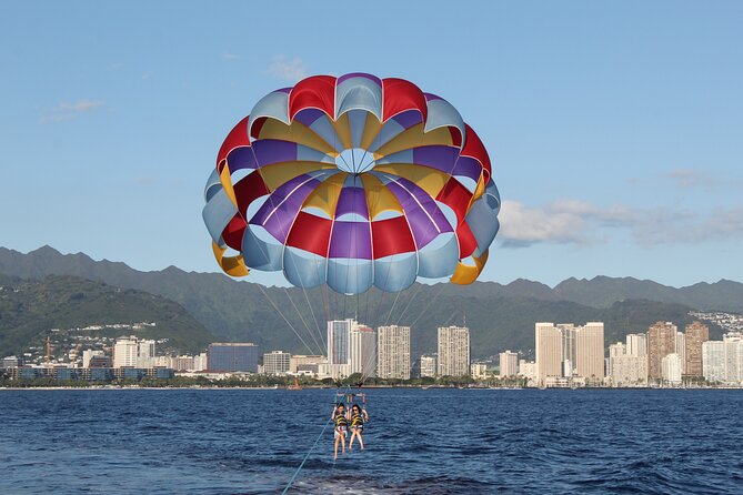 A parasail canopy over the water off Waikiki, with the Honolulu skyline behind